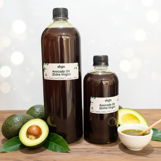 Two bottles of skgn Avocado Oil (Extra Virgin) in different sizes displayed on a wooden counter inside a store with shelves in the background.