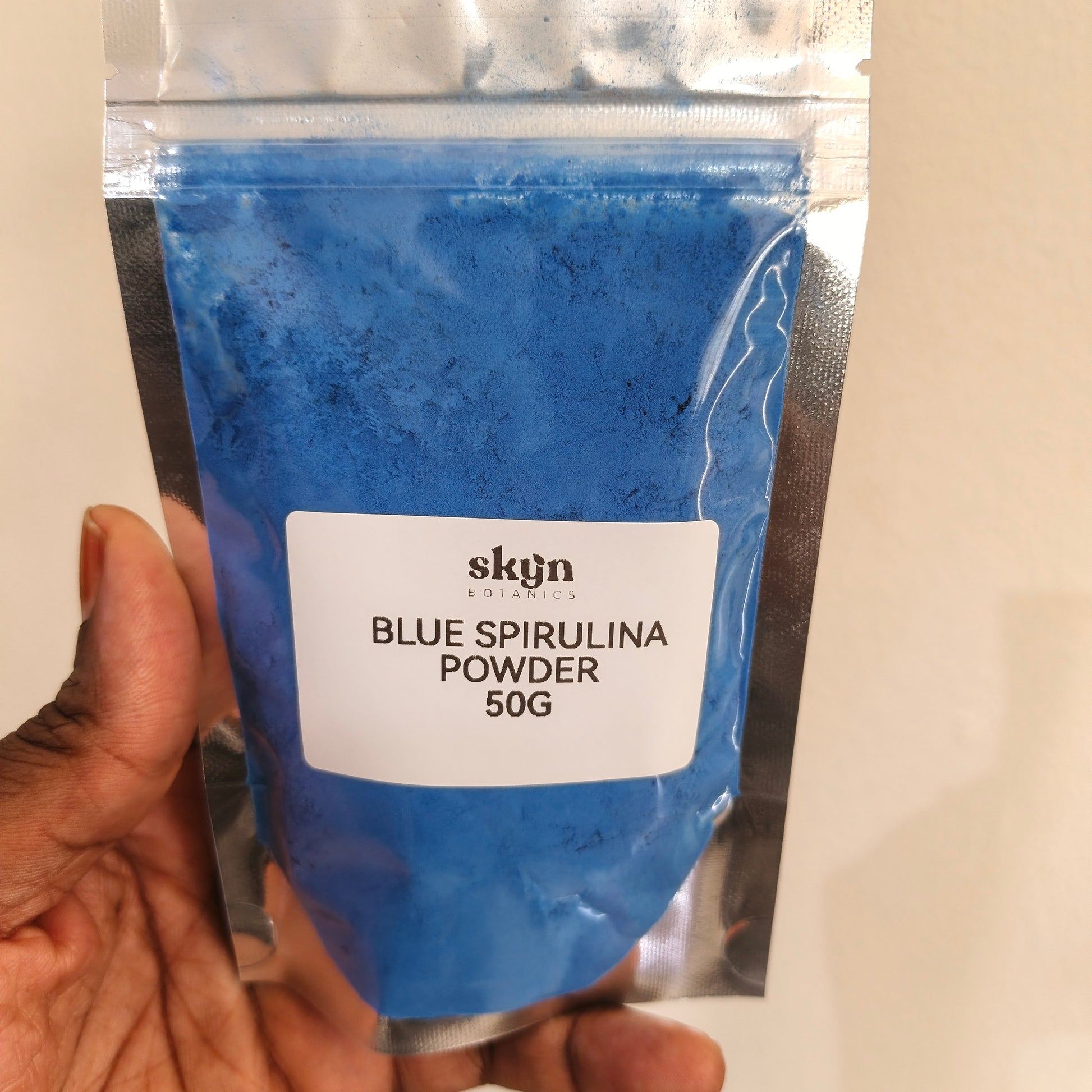 Blue spirulina powder package held by a hand with a visible brand label.
